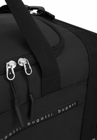 Borsa a duffel nera con tessuto testurizzato, doppie cerniere, tracolla regolabile e un accento di marca che mostra "bugatti" in lettere bianche.