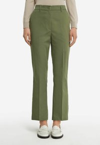 Gröna skräddarsydda byxor med rak skärning, med fåror framtill, sidofickor och knäppning med knapp. Matchas med vita loafers.