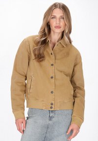 Barna denim dzseki, kihajtós nyakkal, elülső gombos záródással, két oldalsó zsebbel és egy diszkrét horgony logóval a mellkasán.