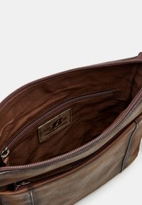 Brown leather bag with a zippered closure, featuring a soft, lined interior and an inner pocket. Label visible on the lining.
