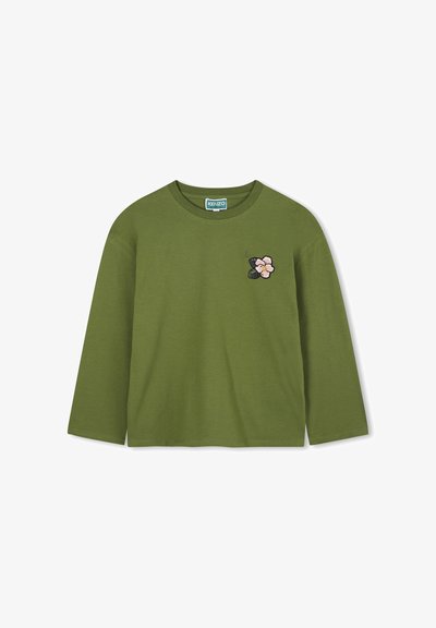 Chemise à manches longues vert olive en coton doux, avec un patch brodé floral rose et noir sur la poitrine gauche. Encolure ronde.