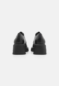 Sapatos de couro pretos com bico arredondado e salto bloco. Textura suave com detalhes de costura discretos na parte de trás.