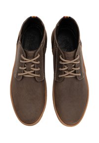 Chaussures en cuir marron avec orteils ronds, lacets beiges et surface texturée. Elles présentent des semelles en caoutchouc marron clair et une étiquette multicolore sur le talon.