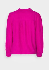 Fuchsia blouse met lange mouwen van textuurstof met kleine geperforeerde patronen, een ronde halslijn en knoopmanchetten.