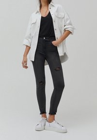 Mustat korkeavyötäröiset kapeat farkut, joissa kuluneet polvivauriot, yhdistettynä valkoiseen ylisuurikokoiseen paitaan ja valkoisiin lenkkareihin. Sileä pinta, rento malli.