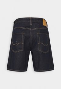 Mörkblå denimshorts med rak skärning, med gula sömmar, två bakfickor och en brun läderpatch på midjan.
