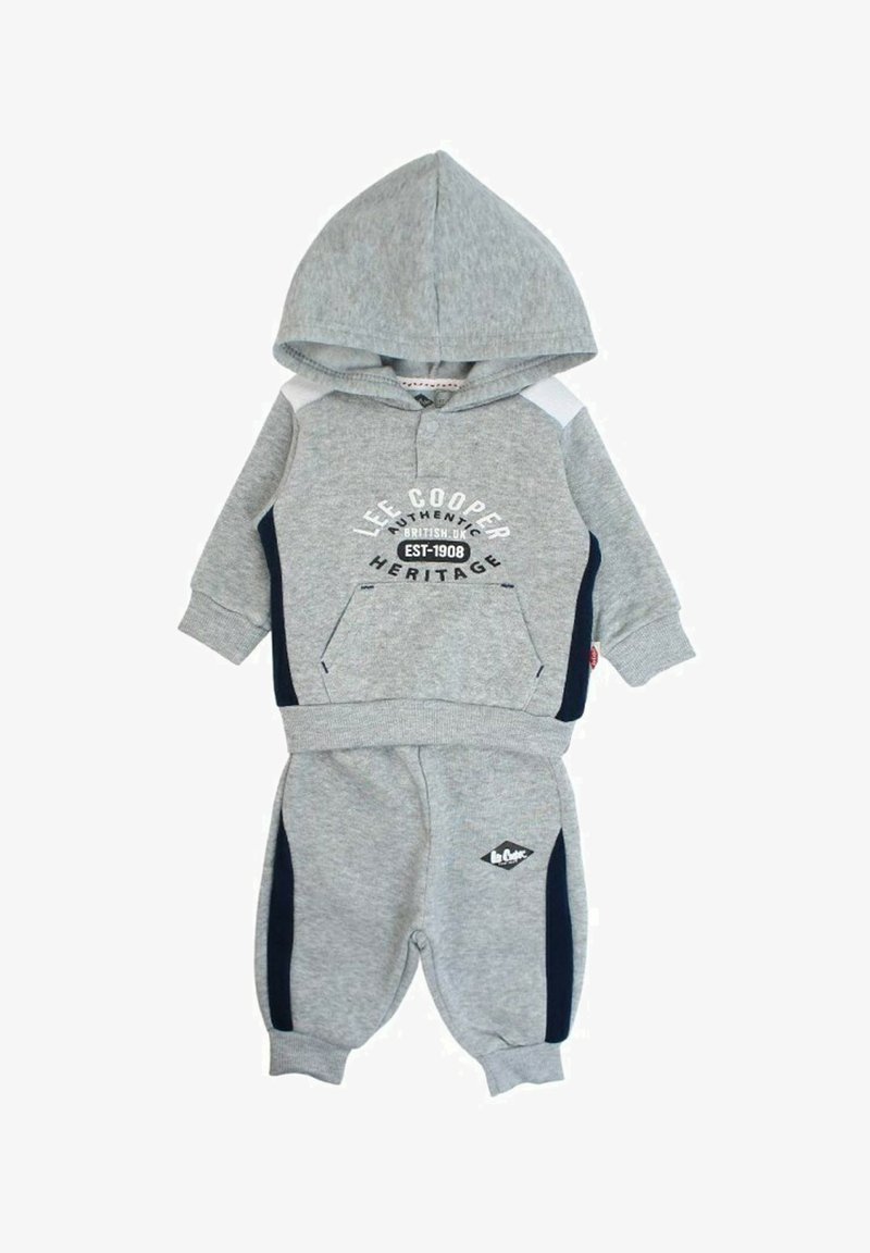 Ensemble sweatshirt gris et pantalon assorti en tissu doux. Comprend une capuche, une poche avant et des rayures latérales bleu marine avec des détails de marque.