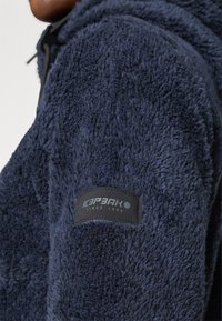 Giacca in fleece blu navy con tessuto morbido e testurizzato. Presenta un'etichetta nera sulla manica con "ICEPEAK" e "SINCE 1996" in grigio.