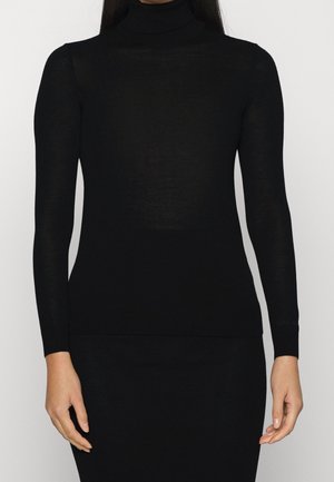 Eng anliegender schwarzer Langarm-Rollkragenpullover, getragen von einer Person, die von Hals bis Hüften vor einem einfarbigen Hintergrund zu sehen ist.