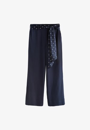 Tumesinised laiade säärtega püksid kõrge vöökohaga ja külge kinnitatud täpiline vöö, mis on ees sõlmes, koos vööaasade ja küljetaskutega.