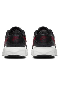 Baskets Nike noires et bourgogne en cuir texturé, avec des accents de logo et une semelle en caoutchouc blanc présentant un motif strié.