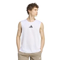 Jeune homme portant un débardeur blanc de sport avec des points texturés et un logo noir, pantalon beige, debout les mains dans les poches, regardant vers la droite.
