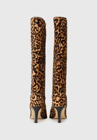 Bottes montantes en imprimé léopard en tissu doux, avec un bout pointu et un talon aiguille de 3 pouces. Accents noirs en haut et sur la semelle.