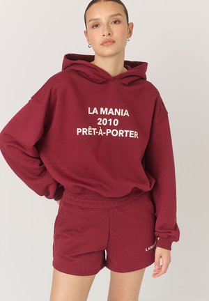 Bordowy, oversize hoodie z białym napisem "LA MANIA 2010 PRÊT-À-PORTER" w komplecie z dopasowanymi szortami, wykonany z bawełny, o casualowym designie.