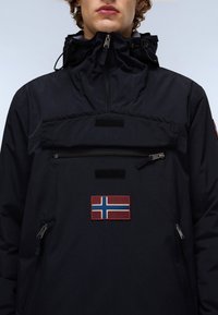 Navy outdoor jacket with a high collar, front zip pocket, and an embroidered Norway flag accent. Made of durable, textured fabric.