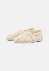 Zapatos de cordones en marfil con un diseño de corte floral. Material suave, puntera redondeada y paneles laterales elásticos para un fácil calzado. Suela de goma plana.