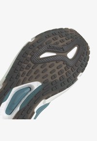 Sula av en löpsko med svart och vit Continental gummisula och teal-färgade dämpningsdelar, utformad för grepp och komfort.