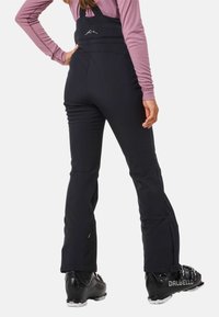 Zwarte skibroeken met verstelbare banden, slim fit, synthetisch materiaal en ritsen bij de enkels. Kenmerkt een bergafbeelding op de achterkant.