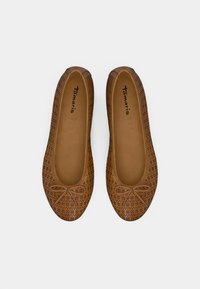 Μπάλες μπαλαρίνες από καφέ δέρμα με τρύπες, στρογγυλή μύτη και μικρή φιόγκο διακόσμηση στο επάνω μέρος. Λείο εσωτερικό επένδυση.