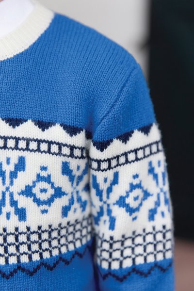 Pleteni pulover z modro-belimi barvami, geometričnimi vzorci, rebrastim ovratnikom in teksturirano tkanino okoli prsnega predela.