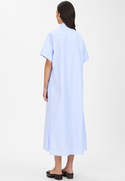 Vestito azzurro chiaro a maniche corte con colletto, di lunghezza lunga e taglio dritto. Il tessuto sembra liscio con cuciture minime.