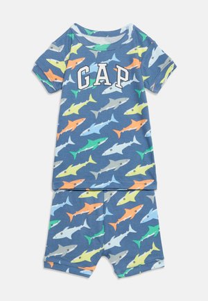 Set de pijama albastru pentru copii, cu mâneci scurte, imprimeuri colorate cu rechini, logo GAP alb pe tricou, pantaloni scurți asortați, așezate plat pe un fundal alb.