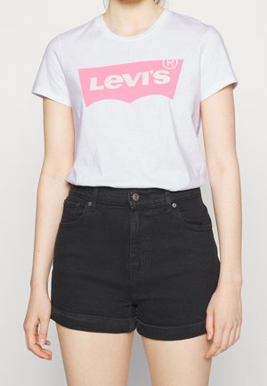 T-shirt en coton blanc avec un logo Levi's rose, associé à un short en denim noir avec des ourlets retroussés et des poches avant.