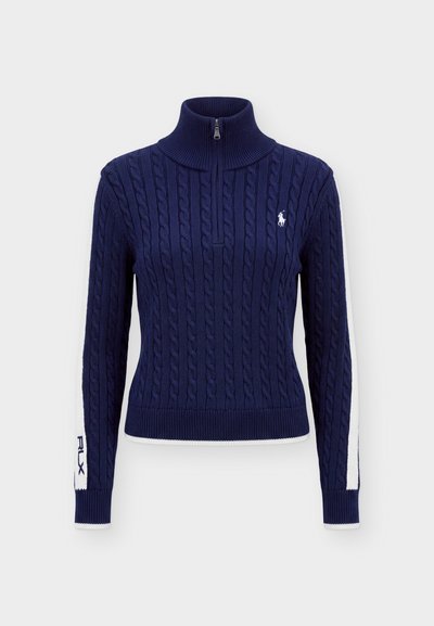 Pull bleu marine en maille torsadée avec col à demi-fermeture éclair, rayures blanches sur les manches et petit logo blanc brodé sur la poitrine.