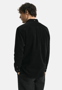 Zwarte corduroy overhemd met een button-down kraag, lange mouwen en een rechte rugpas, voorzien van knoopmanchetten en een relaxte pasvorm.