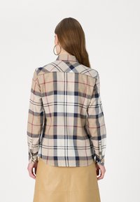 Karierte Hemd in Beige, Marineblau und Rot. Mit langen Ärmeln, Knopfverschlüssen und rundem Saum. Das Material wirkt leicht und strukturiert.