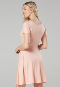 Helles rosa Kurzarmkleid mit tailliertem Oberteil und schwingendem Rock, aus weichem Stoff gefertigt. Verfügt über einen runden Ausschnitt und einen glatten Rücken.