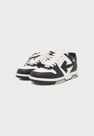 Ζευγάρι μαύρα και λευκά sneakers χαμηλού πάτου με λευκά κορδόνια και χαρακτηριστικό μαύρο σχέδιο βέλους στα πλάγια.