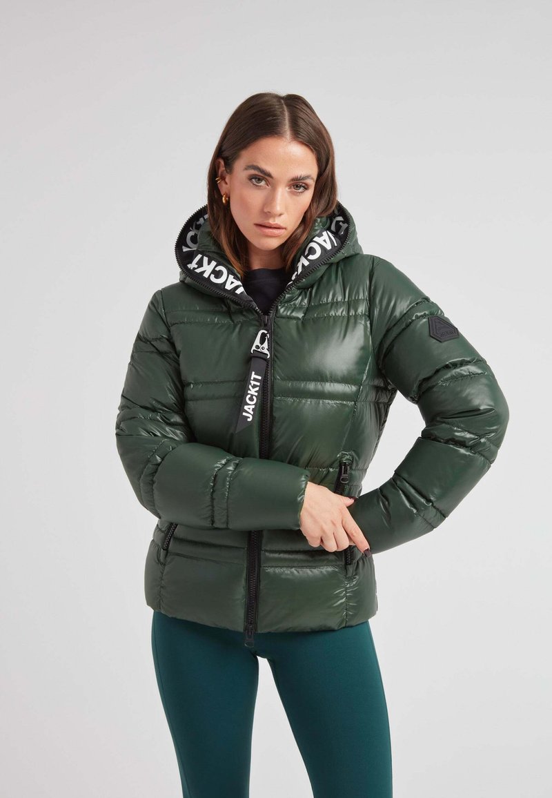 Chaqueta acolchada verde con un acabado brillante, cierre de cremallera, dos bolsillos laterales y una capucha forrada de negro con un patrón de logotipos.