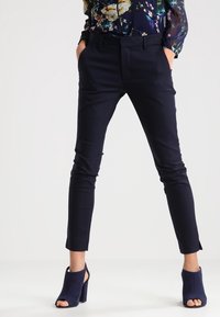 Marina skräddarsydda byxor med slim fit, med en mjuk textur, snedställda fickor och kort längd, i kombination med marina klackade ankelstövlar.