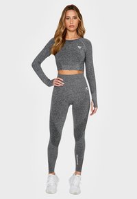 Grey long-sleeve crop top and high-waisted leggings made of textured fabric, featuring a subtle pattern and logo on the waist and chest.