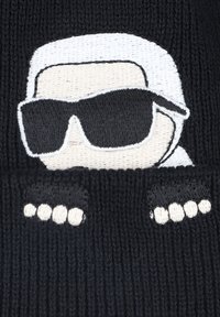 Berretto in maglia nero con personaggio ricamato che indossa occhiali da sole, con capelli e mani bianchi, caratterizzato da un motivo a coste.