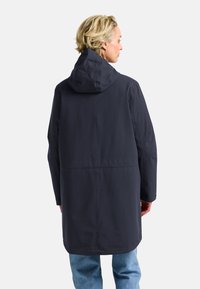 Marineblauw waterdichte parka met capuchon, voorzien van een relaxte pasvorm, een middellange snit en zichtbare stiknaaddetails op de rug en mouwen.