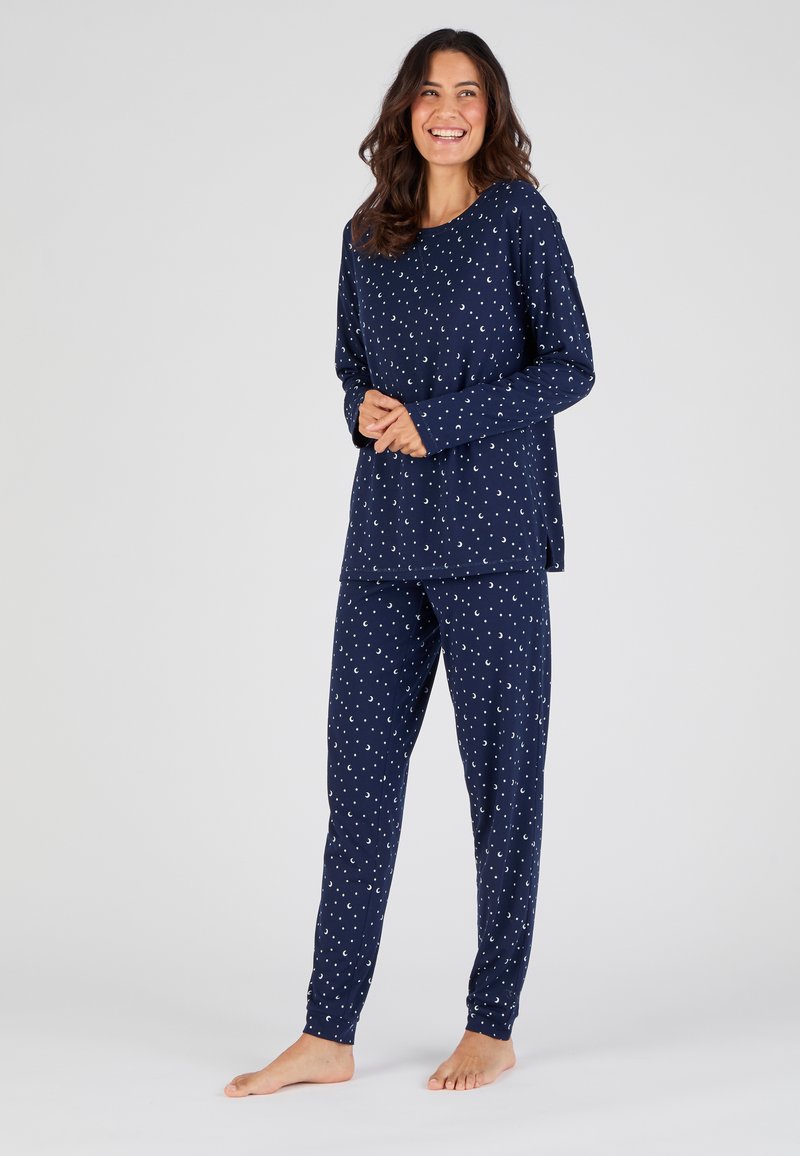 Navyblauwe pyjama-set van zacht katoen, bestaande uit een langemouwen top en slim-fit broek, beide versierd met witte maanpatronen.