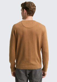 Bruine gebreide trui met lange mouwen, ronde hals en geribbelde zoom. Gemaakt van zacht materiaal, met een minimalistisch design.