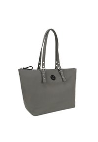 Grå totebag tillverkad av slitstark tyg, med dragkedjestängning, dekorativa nitar på remmarna och en rund svart logotypdetalj.