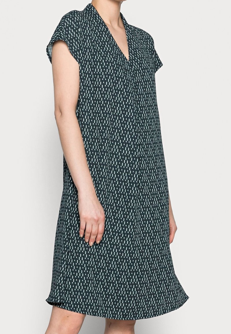 Zelené šaty s krátkým rukávem, v výstřihem do V, uvolněným střihem, jemnými bílými vertikálními vzory a bočními rozparky na spodním lemu.