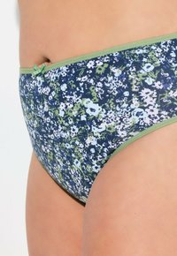 Costume da bagno a vita alta con un motivo floreale blu navy che presenta fiori verdi e azzurri. Rifinito con un bordo verde e un fiocco decorativo.