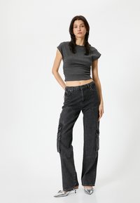 Top corto gris con tejido texturizado, combinado con pantalones cargo negros holgados con bolsillos laterales. El calzado incluye tacones metálicos plateados.