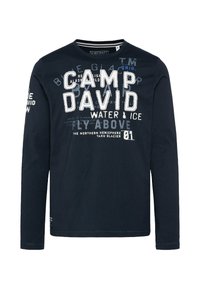 Granatowa koszulka z długim rękawem, wykonana z bawełny, z nadrukowanym białym i niebieskim tekstem, w tym "CAMP DAVID" oraz różnymi graficznymi akcentami.