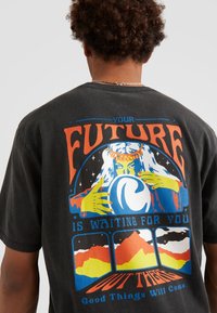 T-shirt in cotone nero con un design grafico colorato sulla schiena. I colori principali includono arancione, verde, blu e giallo, rappresentando montagne e mani.