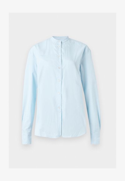 Ανοιχτό μπλε πουκάμισο με μακριά μανίκια, κουμπιά, γιακά μπάντα και ελαφρώς καμπυλωτό τελείωμα, εμφανίζεται σε απλό φόντο.