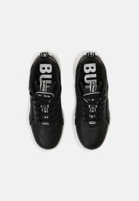 Baskets en cuir noir avec des lacets blancs et une semelle extérieure blanche. Grand texte « BUFFALO » sur la semelle intérieure et petit logo sur le côté.