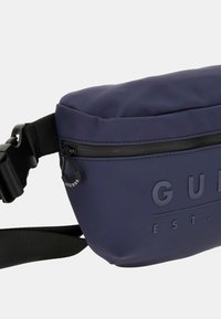 Marsupio in nylon blu navy con finitura opaca, dotato di tasca frontale con zip e logo impresso. Cintura regolabile per una vestibilità sicura.