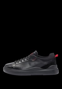 Baskets en cuir noir avec une texture lisse, dotées de lacets noirs, d'une semelle noire mate et d'un accent de logo rouge sur le côté et le talon.