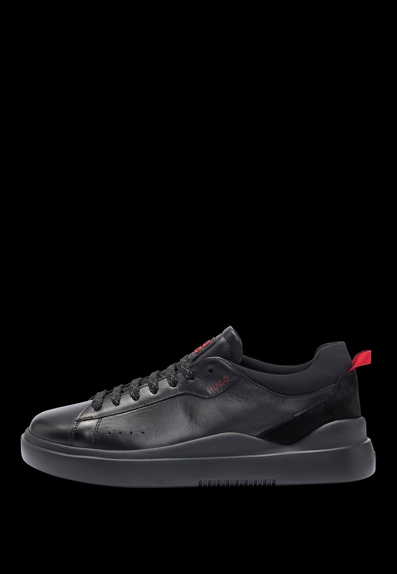 Baskets en cuir noir avec une texture lisse, dotées de lacets noirs, d'une semelle noire mate et d'un accent de logo rouge sur le côté et le talon.